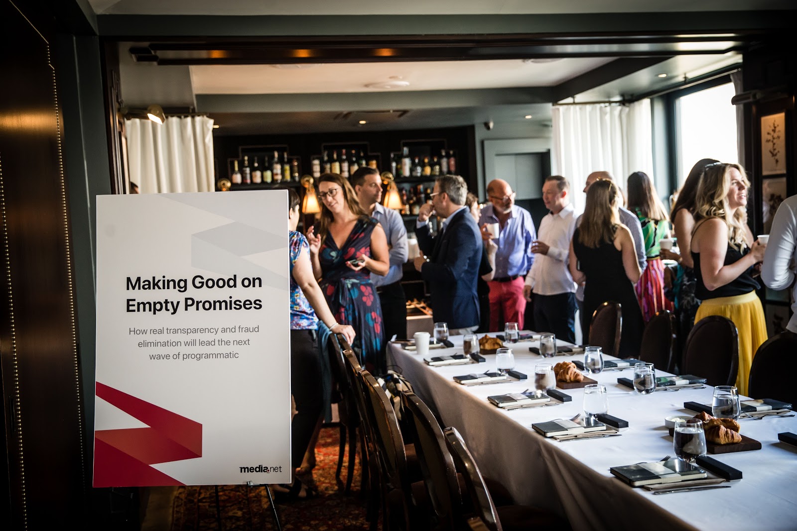 Media.net leadership breakfast event featuring adtech industry executives discussing transparency and fraud, with a visible event poster titled 'Making Good on Empty Promises' in the foreground